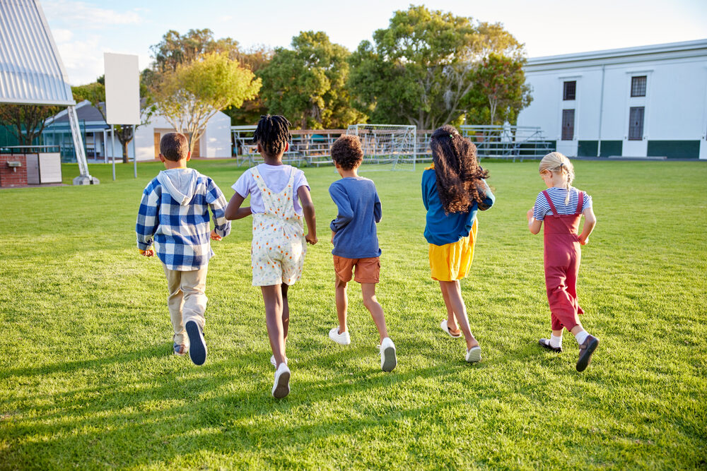 Kinder rennen über eine Wiese auf dem Sportplatz