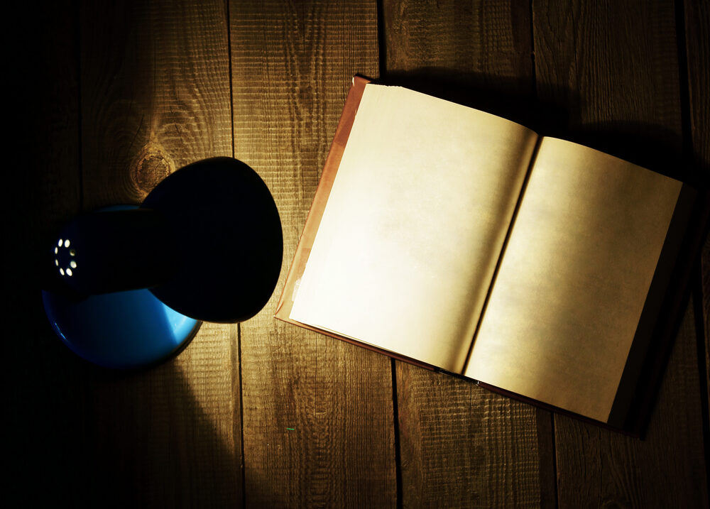 Aufgeschlagenes Buch, beleuchtet von einer Taschenlampe in der Nacht
